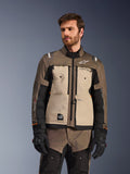 Alpinestars Cusco Drystar® jakke, adventure motorcykeljakke, Walnut Aluminum Black, vist på en model med sorte handsker, med sandfarvede brystpaneler og sorte ærmer med Alpinestars-branding og All Terra-mærke, beskyttende touring-udstyr til al slags vejr