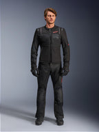 Mandlig model iført Alpinestars ST-2 Air-jakke, sort motorcykeljakke med mesh-paneler og rødt logo, 'Alpinestars Exploration Equipment'-tekst på brystet, kombineret med sorte tekniske kørebukser og handsker, moderne adventure touring-udstyr