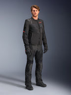 Mandlig model iført Alpinestars ST-2 Air-jakken i sort, med et rødt stjernelogo og 'Alpinestars Exploration Equipment'-branding, kombineret med matchende sorte kørebukser, handsker og støvler til et moderne sommer-touring-outfit.