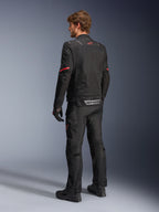 Alpinestars ST-2 Air Jakke, sort motorcykeljakke, set bagfra på model med et rødt stjernelogo øverst på ryggen og reflekterende Alpinestars-branding ved taljen, kombineret med matchende sorte tekniske kørebukser og handsker.