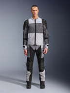 Alpinestars ST-2 Air Jakke, motorcykel touring-jakke, Ice Gray, Dark Gray og sort, båret af en model med matchende adventure-bukser, med store mesh-paneler, blåt Alpinestars-logo på brystet og Alpinestars Exploration Equipment-branding