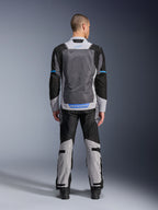 Alpinestars ST-2 Air-jakke, isgrå, mørkegrå og sort, set bagfra på model, med store mesh-ventilationspaneler, blå detaljer og Alpinestars-logo, kombineret med matchende motorcykelbukser til adventure touring.