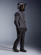 Motorcykelrytter iført Alpinestars Maxdura Drystar®XF Laminated Armored Shell-jakke i mørkegrå og sort, kombineret med sorte adventure-kørebukser, sort hjelm med goggles, sorte handsker og støvler, helkrops-studiebillede der fremhæver det tekniske dual-sport-udstyr.