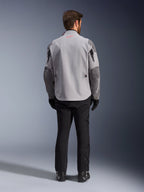 Alpinestars Maxdura Drystar®XF Laminated Armored Shell, mellemgrå og mørkegrå motorcykeljakke, set bagfra, med en lysegrå krop og mørkegrå paneler på skuldre og ærmer, lille rødt Alpinestars-stjernelogo på kraven bagpå og hvid branding på venstre underærme, kombineret med sorte kørebukser og støvler.