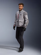 Alpinestars Maxdura Drystar®XF Lamineret Armored Shell, adventure-motorcykeljakke, mellemgrå og mørkegrå, båret af en model med sorte kørebukser og handsker, med røde lynlåsdetaljer og cargo-lommer, professionelt teknisk udstyr til al slags vejr til adventure touring