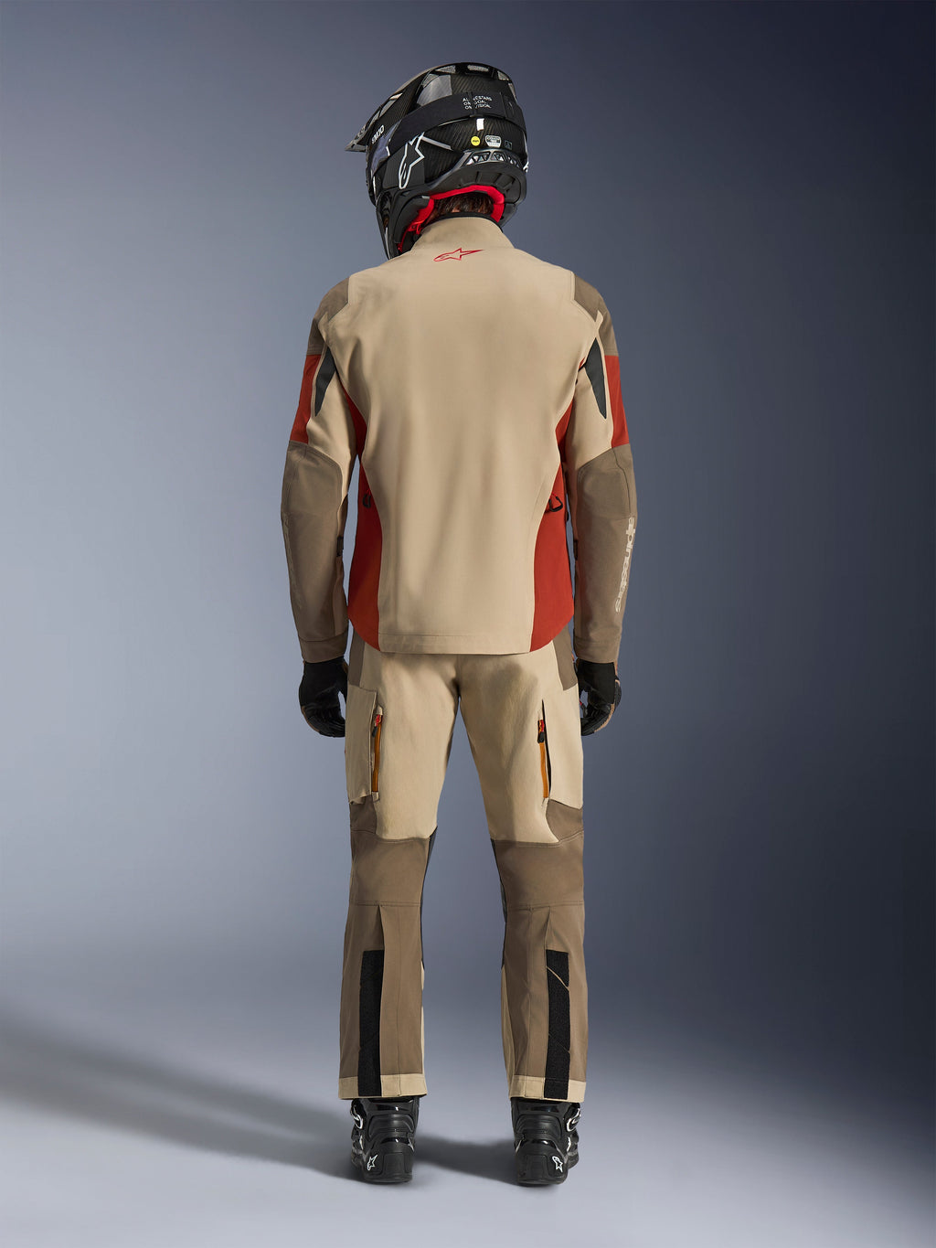 Alpinestars Maxdura Drystar®XF Laminated Armored Shell, adventure-motorcykeljakke og matchende bukser, Aluminum Walnut og Rust Brown farvevariant, rygvisning af kører med sort hjelm og støvler, professionelt adventure-touring-udstyr