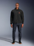 Alpinestars Revved WR-jakke i sort, båret af en model med mørkeblå jeans og sorte sneakers, set forfra, med trykknaplukning og et 3D-broderet logo på brystet, urbant moderne motorcykeludstyr