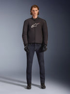 Model iført Alpinestars SMX Vandtæt Jakke i sort med hvidt og rødt logo, kombineret med mørke denim motorcykelbukser, sorte handsker og motorcykelstøvler, sporty motorcykeludstyr til al slags vejr
