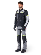 Alpinestars Bogotá Pro Drystar® jakke, adventure touring motorcykeljakke, Black Ice Gray Yellow Fluo, båret af model med matchende bukser og sorte handsker, med vandtæt tekstilkonstruktion, ventilationspaneler og fluorescerende detaljer.