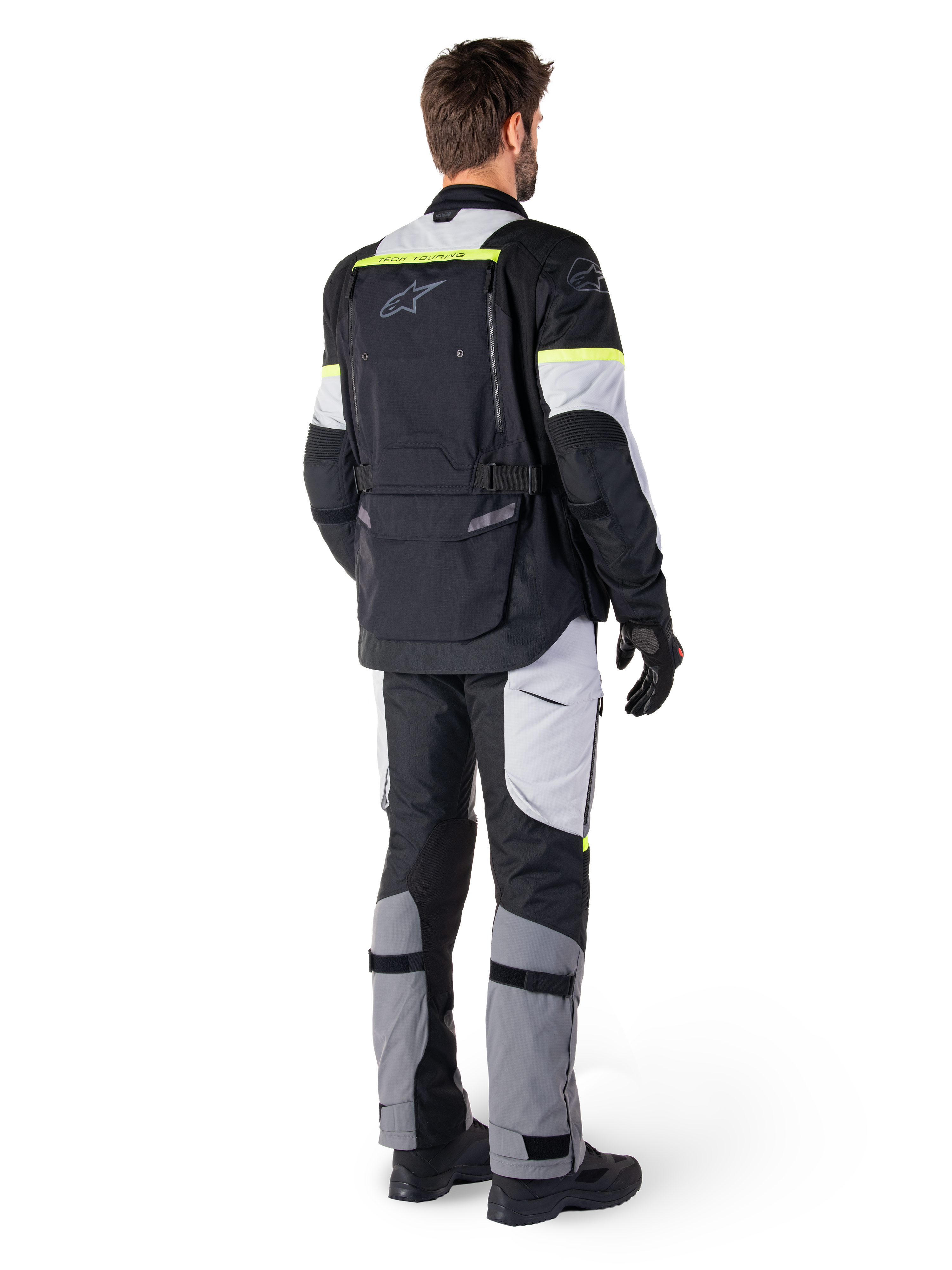 Bagfra set af en motorcyklist iført Alpinestars Bogotá Pro Drystar®-jakke i Black Ice Gray Yellow Fluo, kombineret med matchende adventure touring-bukser, med en stor baglomme og gule fluorescerende detaljer, helårs tekstil motorcykeludstyr.