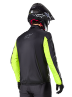 Alpinestars Bogotá Pro Drystar® jakke, set bagfra, sort med Yellow Fluo-ærmer, båret af en kører med sort hjelm og handsker, adventure touring motorcykeludstyr med høj synlighed og teknisk tekstilfinish.