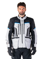 Alpinestars Bogota Pro Drystar jakke, adventure touring-motorcykeljakke, Ice Gray med sorte og cyanblå detaljer, set forfra med ventilationspaneler og cargolommer, båret af en model med sorte kørebukser og handsker