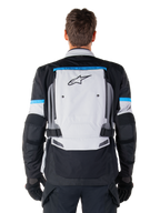 Alpinestars Bogota' Pro Drystar® jakke, adventure-motorcykeljakke, Ice Gray Black og Cyan, set bagfra med et stort lysegråt panel med sort stjerne-logo, cyanfarvede detaljer med Tech Touring-branding og justerbare taljeremme