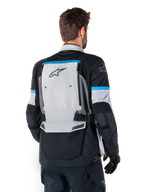Alpinestars Bogota' Pro Drystar® Jakke, adventure-motorcykeljakke, isgrå, sort og cyan, set bagfra med fokus på det store grå rygpanel med Tech Touring-branding, cyan-accenter på ærmerne og holdbar tekstilkonstruktion.