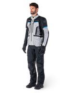Mandlig kører iført Alpinestars Bogotá Pro Drystar®-jakke i Ice Gray, sort og cyan, kombineret med sorte tekniske kørebukser og handsker, adventure touring-udstyr til ydeevne i al slags vejr.