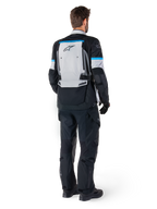 Alpinestars Bogota' Pro Drystar® jakke, adventure-motorcykeljakke, Ice Gray, sort og cyan, set bagfra, båret med matchende sorte bukser og handsker, med et stort gråt rygpanel, sort Alpinestars-logo og cyanblå accenter.