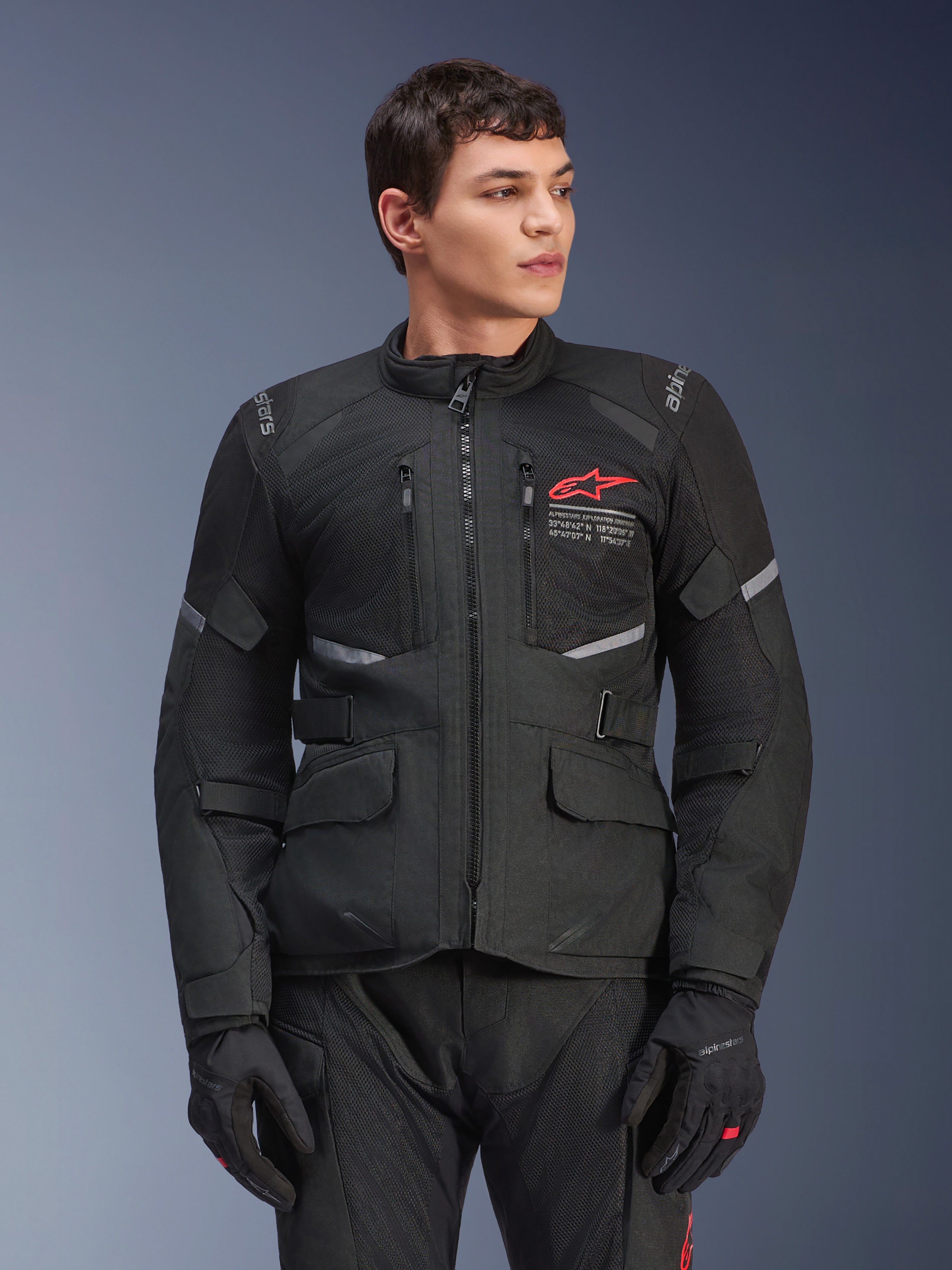 Alpinestars Andes Air Drystar®-jakke, sort motorcykeljakke til touring, rødt stjernelogo på brystet, med ventilationspaneler i mesh og reflekterende detaljer, båret af en mandlig model med sorte kørehandsker, adventure-udstyr til to sæsoner
