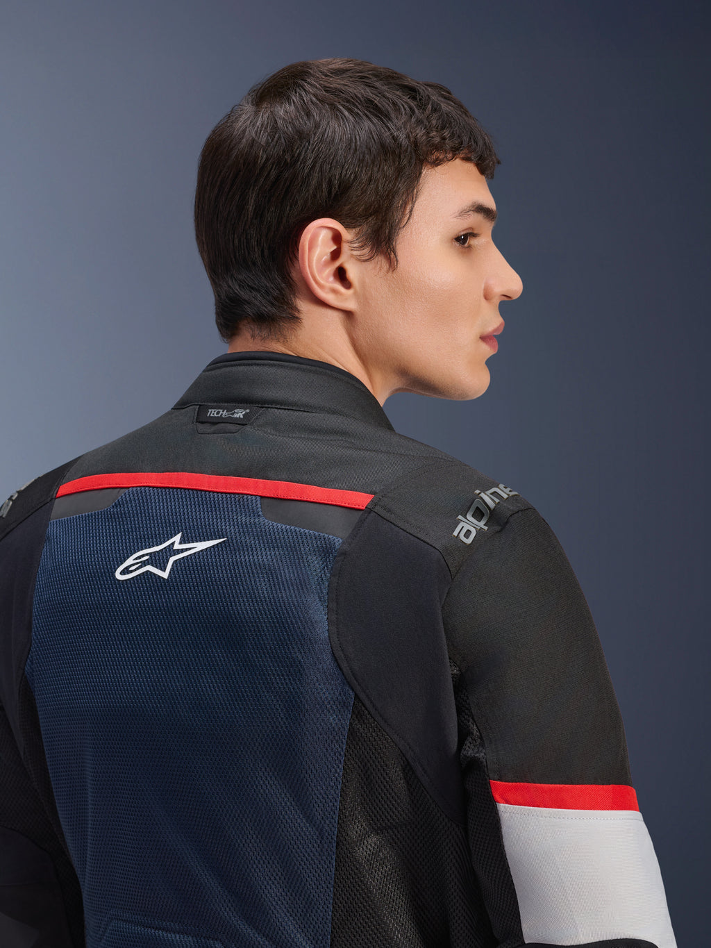 Alpinestars Andes Air Drystar® Jakke, mørkeblå, sort og isgrå, nærbillede set bagfra på en model, med et åndbart mesh-panel med hvidt stjernelogo, røde detaljer og Tech-Air®-branding på kraven, touring-motorcykeludstyr til to sæsoner