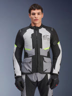 Mandlig kører iført Alpinestars Andes Air Drystar®-jakke i Ice Gray, Dark Gray og sort, med neongule detaljer og mesh-ventilationspaneler, kombineret med matchende motorcykelbukser og handsker, adventure touring-udstyr