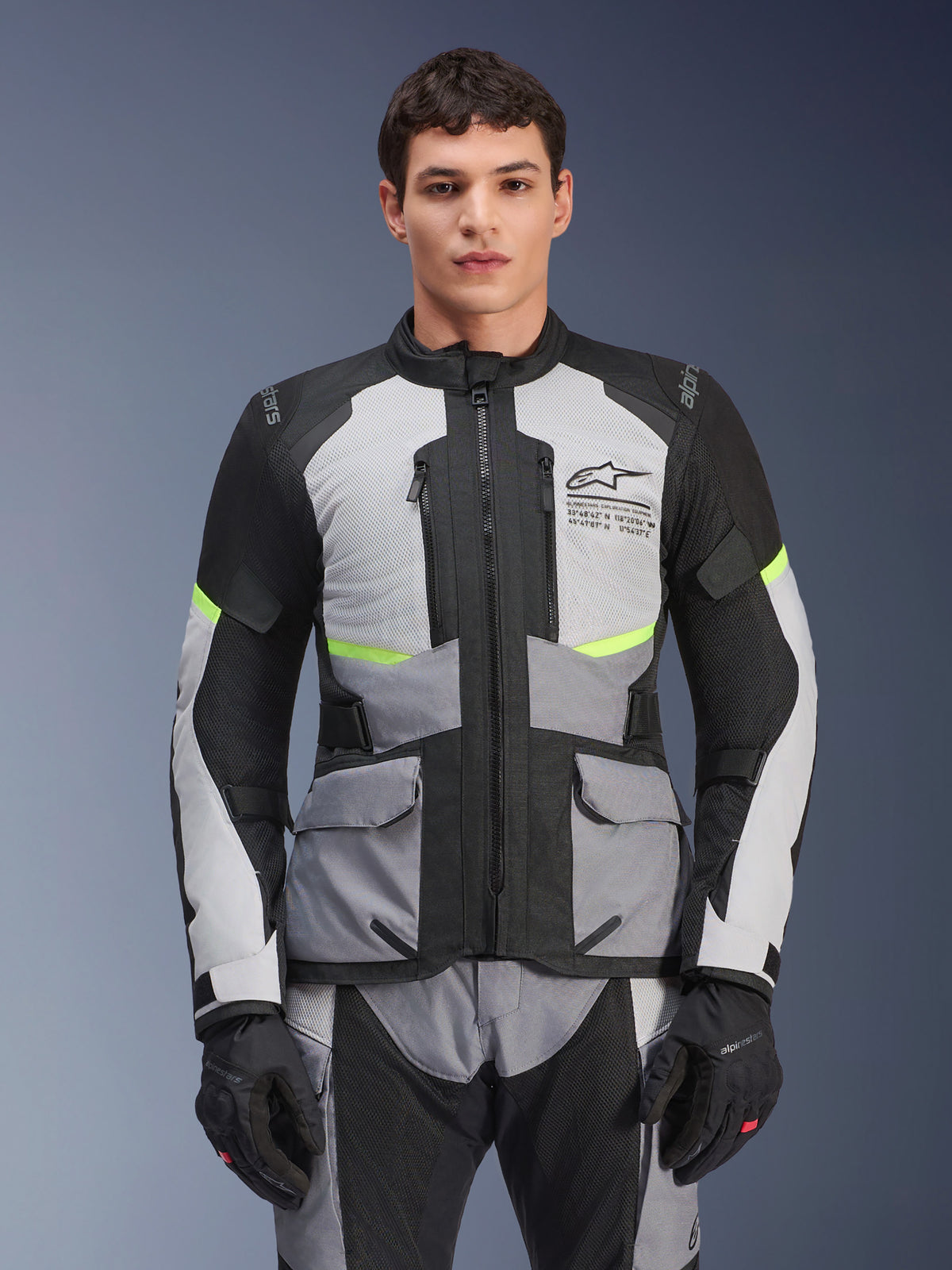 Alpinestars Andes Air Drystar jakke, Adventure Touring motorcykeljakke, isgrå og mørkegrå med sorte paneler og neongule detaljer, båret med matchende bukser og handsker, med mesh-ventilationspaneler og cargolommer