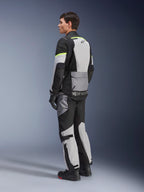 Motorcyklist iført Alpinestars Andes Air Drystar® jakke og bukser, adventure touring-udstyr i Ice Gray Dark Gray Black med neongule detaljer, omfattende mesh-paneler for luftstrøm, Alpinestars-branding på ryggen, vist med sorte handsker og støvler.