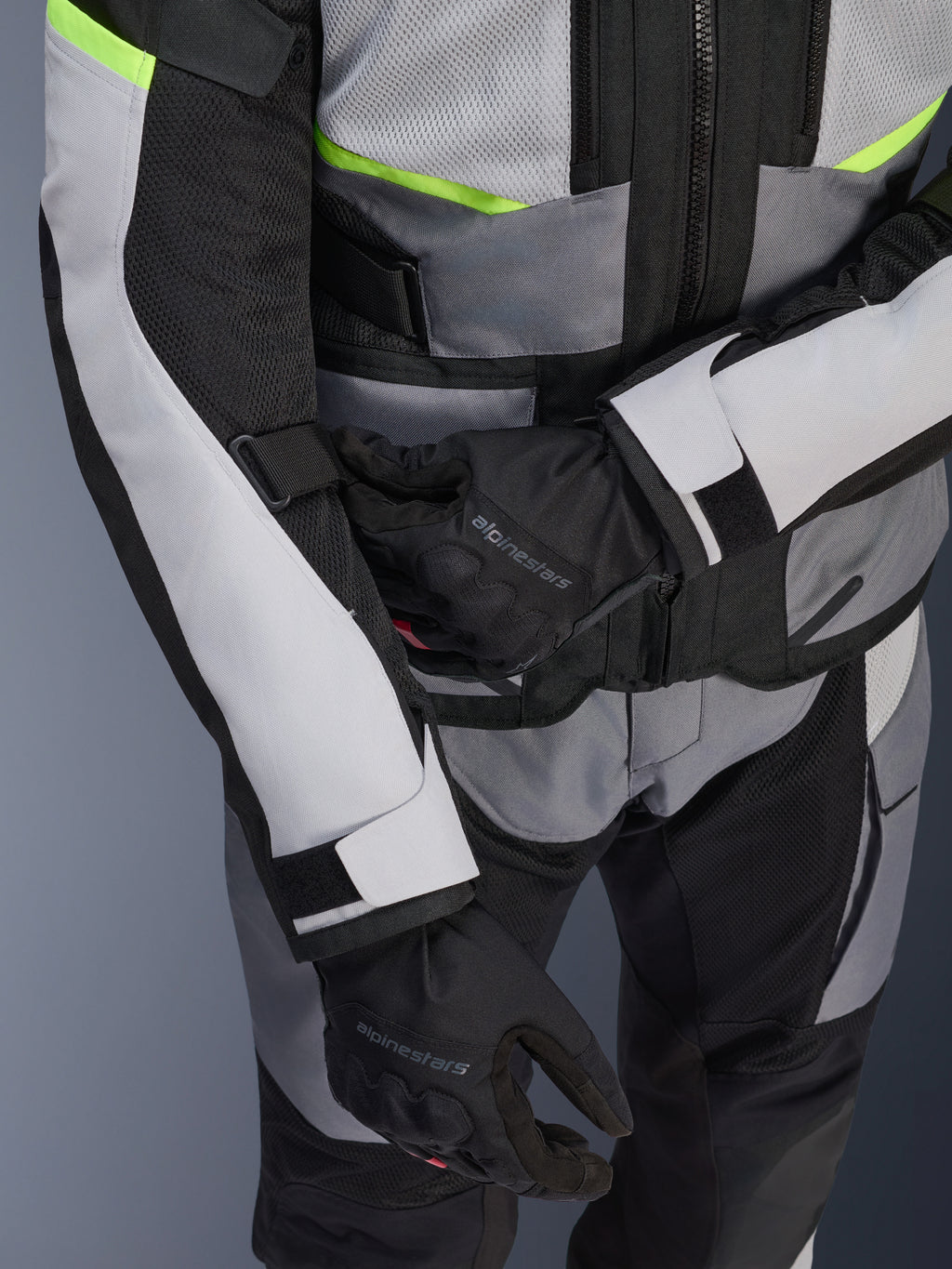 Alpinestars Andes Air Drystar® jakke, touring-motorcykeljakke, Ice Gray og Dark Gray med neon-gule detaljer, tætbillede der viser mesh-paneler og justeringsstropper, bæres med sorte Alpinestars-handsker