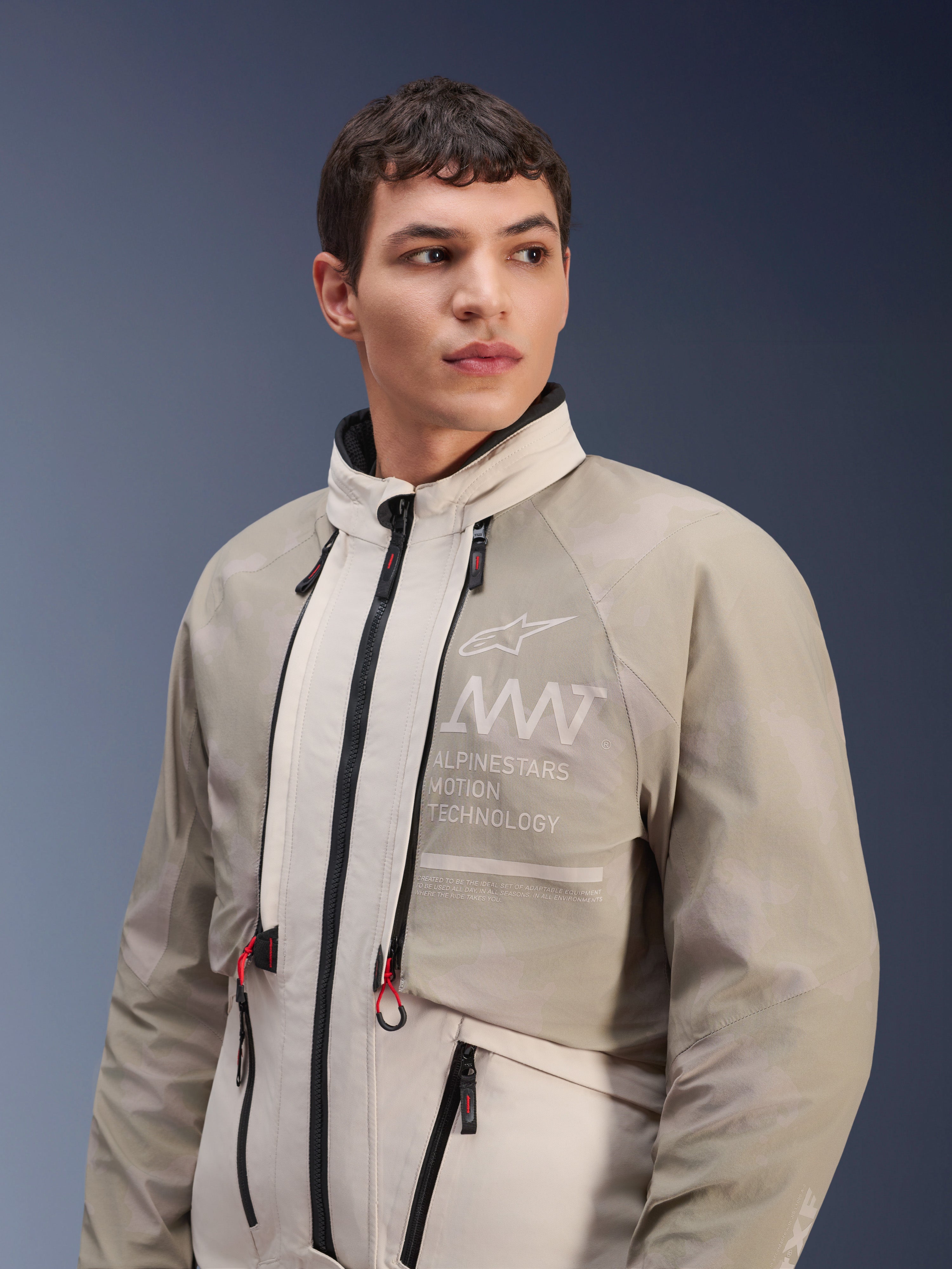 Alpinestars AMT-10LAB Drystar® XF-jakke, White Sand Aluminum Camo, modulær adventure-motorcykeljakke, med 'Alpinestars Motion Technology'-branding på brystet, båret af en mandlig model.