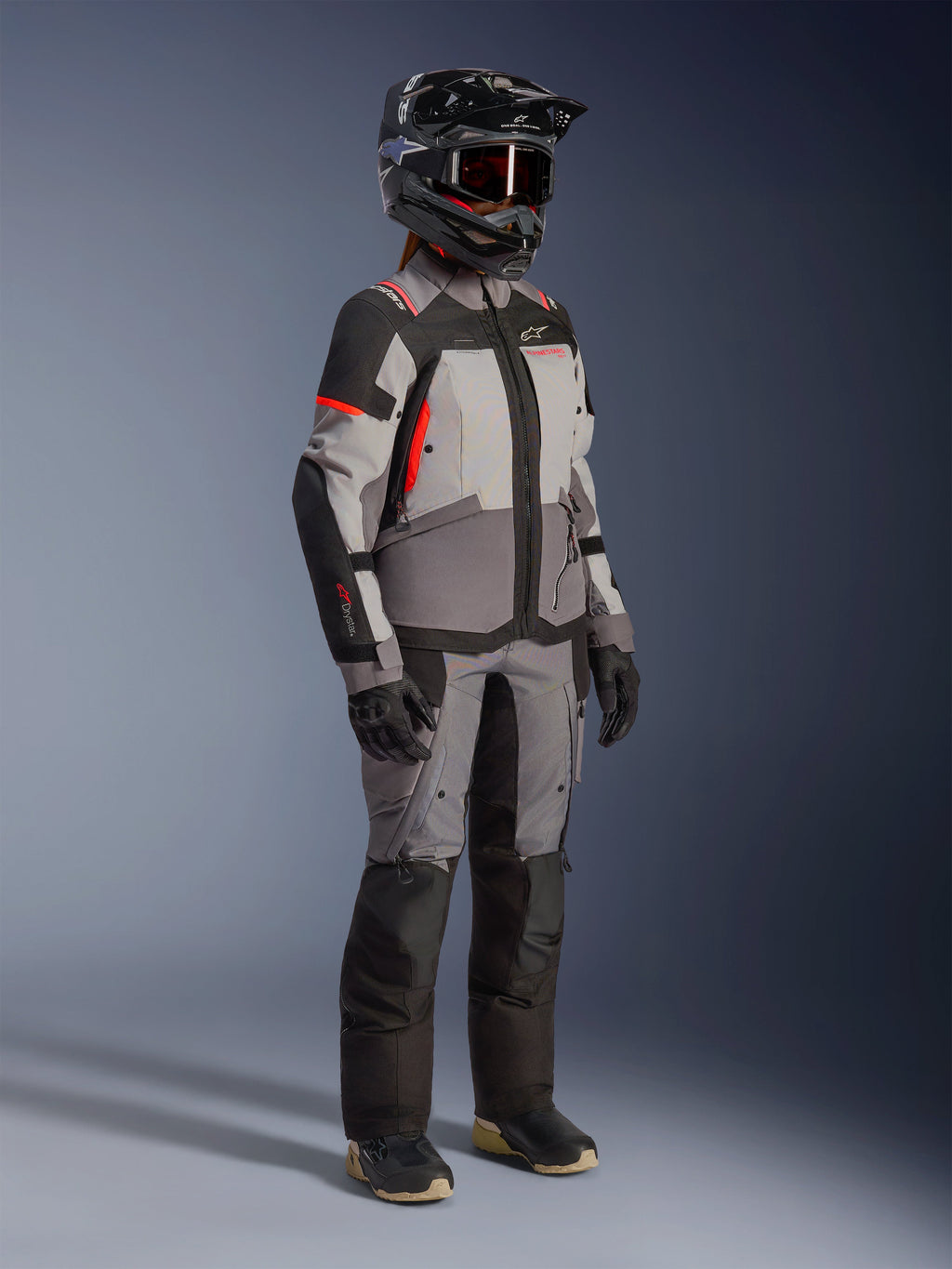 Alpinestars Stella Andes V4 Drystar® dame-motorcykeljakke til adventure-touring, grå og sort med koralrøde detaljer, vandtæt og åndbar, båret af en rytter.