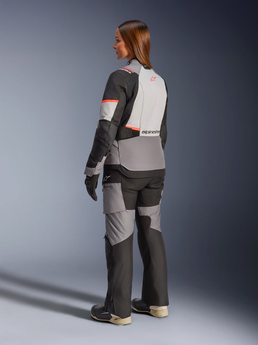 Alpinestars Stella Andes V4 Drystar-jakke, vandtæt adventure-motorcykeljakke til damer, grå og sort med koralfarvede detaljer, set bagfra.