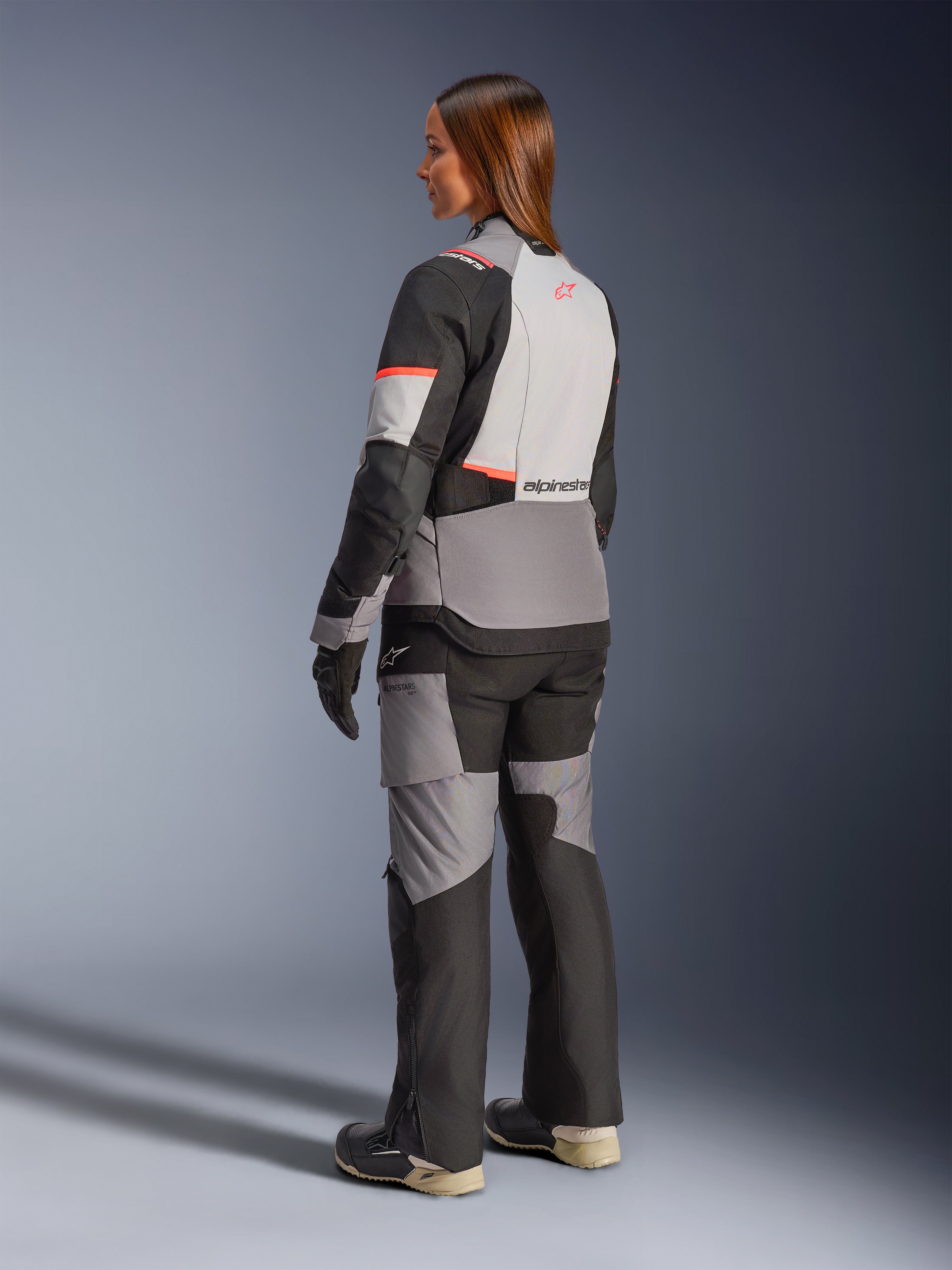 Alpinestars Stella Andes V4 Drystar-jakke, vandtæt adventure-motorcykeljakke til damer, grå og sort med koralfarvede detaljer, set bagfra.