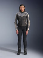 Kvinde iført Alpinestars Stella T-Dyno WR-jakke, sort, mørkegrå og ecru, frontvisning, tekstil-motorcykeljakke med vintage-inspireret design, med logoer på bryst og ærmer, båret sammen med sorte bukser og støvler