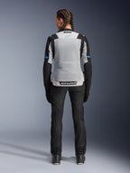 Alpinestars Stella ST-2 Air jakke, Ice Gray Black, set bagfra på en kvindelig model, med et stort lysegråt mesh-rygpanel, sorte ærmer med blå stribedetaljer, Alpinestars-branding på den nederste del af ryggen, kombineret med sorte tekniske kørebukser og støvler, sommer-motorcykel-touringudstyr