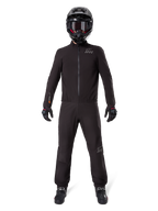 Motorcykelrytter iført Alpinestars AMT-8 Stretch Drystar® XF bukse-liner og matchende jakke, helsort vandtæt og vindtæt teknisk udstyr, med sort hjelm, handsker og støvler, strømlinet adventure touring-design