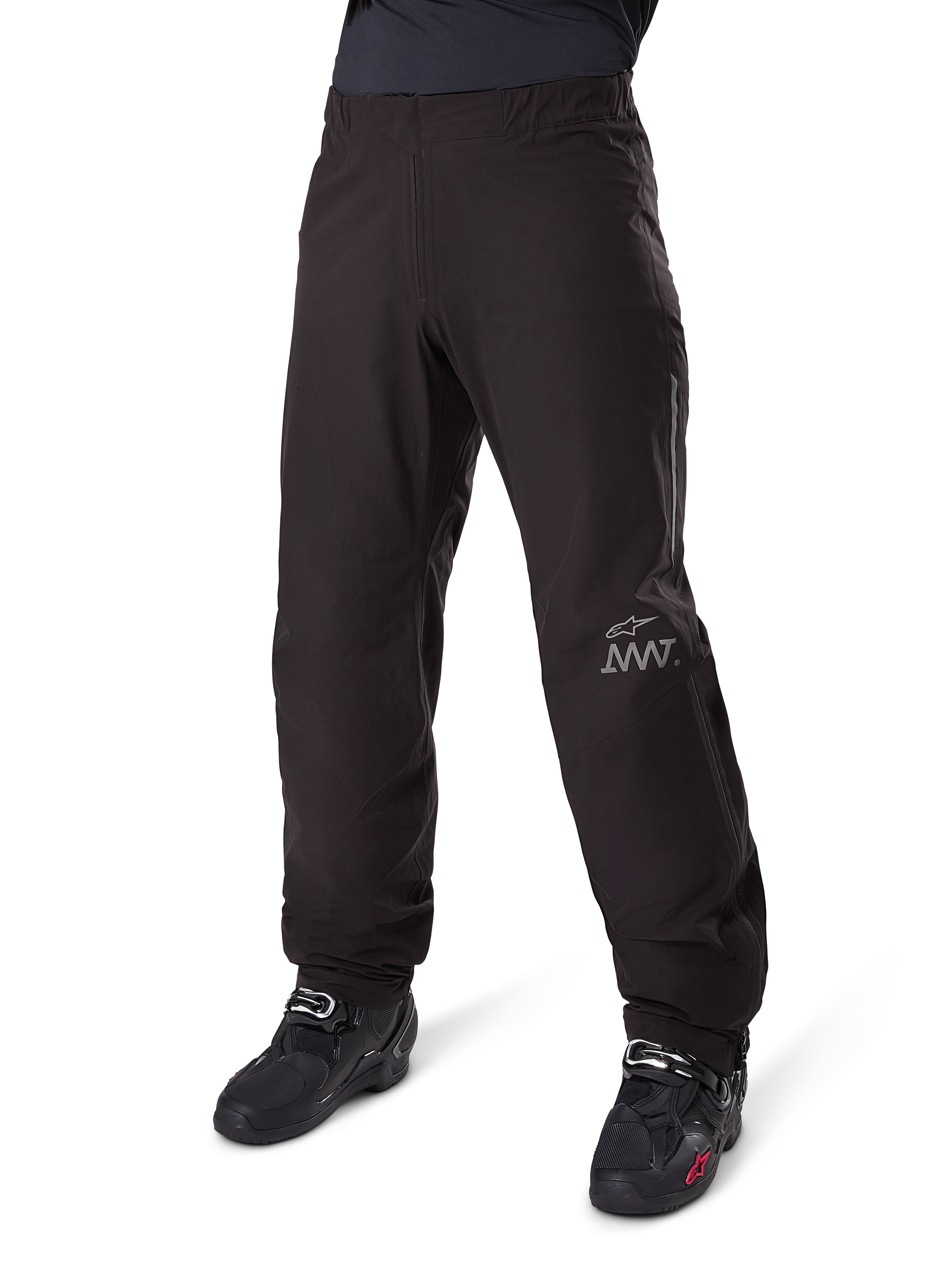 Alpinestars Amt-8 Stretch Drystar® XF bukse-liner, sort, vandtæt og strækbar tekstilkonstruktion med sølvfarvet AMT-logo, båret med sorte motorcykelstøvler, adventure touring motorcykeludstyr