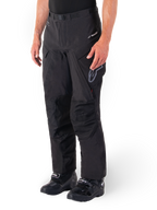 Alpinestars Hyde XT Drystar® bukser, Adventure Touring motorcykelbukser, sorte, vist med sorte støvler, med lamineret Drystar®XF-membran-branding, forstærkede knæpaneler og cargolommer med lynlås.