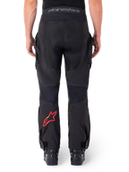 Alpinestars Hyde XT Drystar® bukser, adventure-motorcykelbukser, sorte med rødt stjernelogo på underbenet, set bagfra, over-the-boot enduro-design med slidstærke tekstilpaneler og taljebånd med logo
