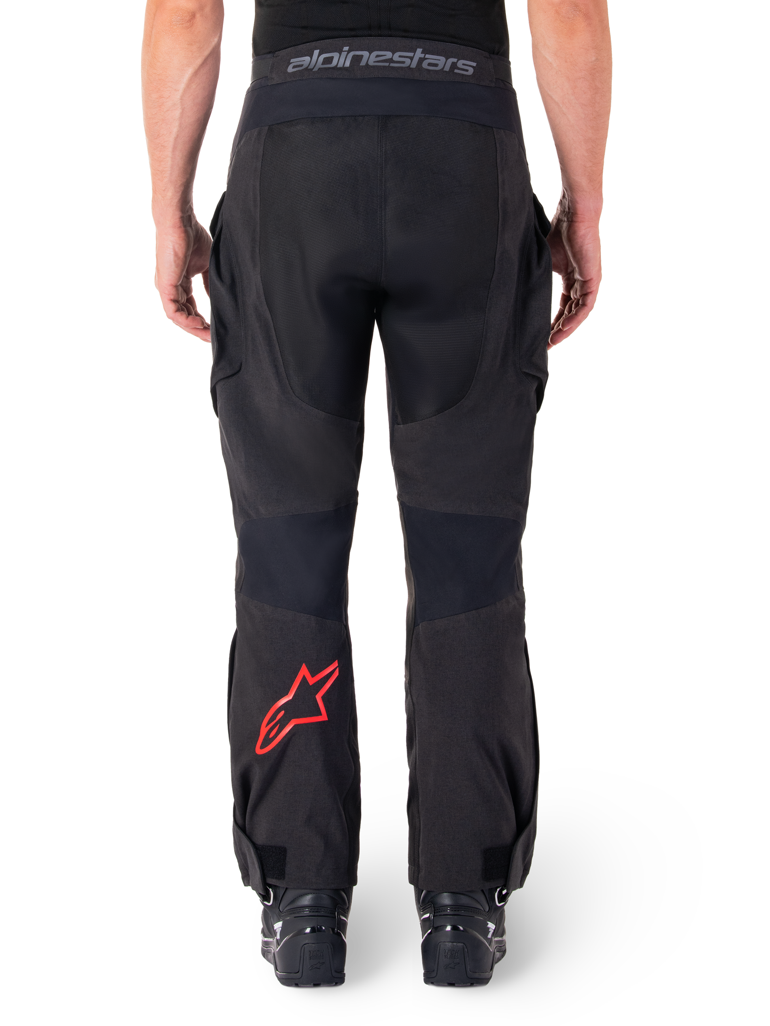 Alpinestars Hyde XT Drystar® bukser, adventure-motorcykelbukser, sorte med rødt stjernelogo på underbenet, set bagfra, over-the-boot enduro-design med slidstærke tekstilpaneler og taljebånd med logo