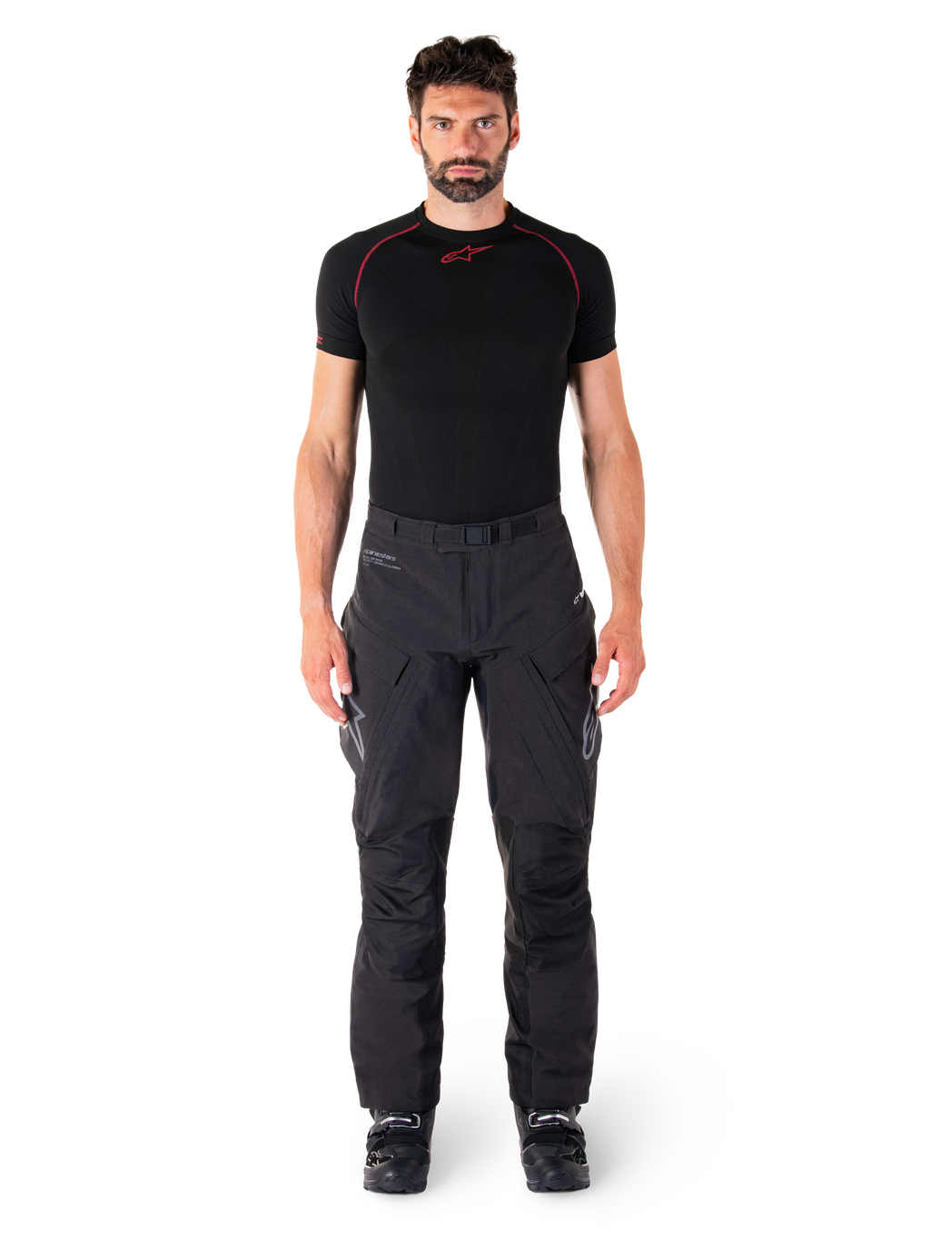Alpinestars Hyde XT Drystar® bukser, Adventure Touring motorcykelbukser, sort, båret af en model med et sort kortærmet basislag og sorte støvler, med teknisk strækmateriale, forstærkede knæpaneler og ergonomiske cargolommer