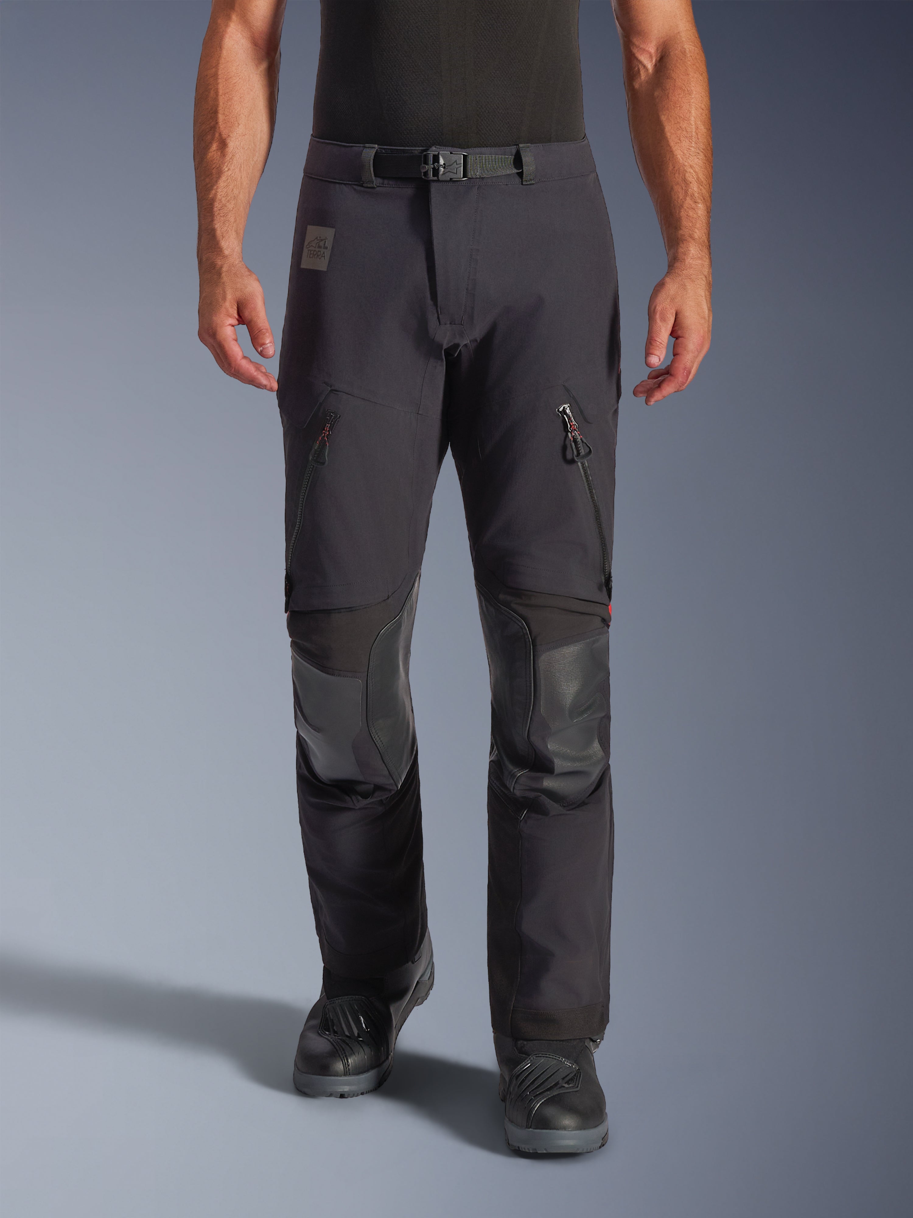 Alpinestars Halo Pro Drystar® XF laminerede bukser i Black Dark Shadow, adventure-motorcykelbukser, set forfra på model med magnetisk taljespænde, ventilationsåbninger med lynlås på lårene og forstærkede læderlapper på knæene, kombineret med sorte mc-støvler
