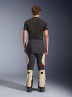 Alpinestars Halo Pro Drystar® XF laminerede bukser, Mastic Black, set bagfra på en model, sort og beige farveblokering med orange logoer, adventure motorcykel touringbukser med holdbar tekstilkonstruktion og justerbare lægsektioner