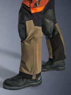 Alpinestars Halo Pro Drystar® XF laminerede bukser, adventure motorcykelbukser, Walnut Rust og sort, detaljebillede med forstærkede knæpaneler og orange branding, båret med sorte touringstøvler, slidstærk tekstilkonstruktion til terrænkørsel
