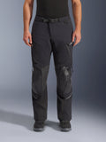 Alpinestars Andes Pro Drystar® XF bukser, sort mørkegrå adventure touring motorcykelbukser, set forfra, med 3-lags lamineret konstruktion, integrerede knæbeskyttelsespaneler, vandtætte lynlåslommer og magnetisk taljespænde, stylet med sorte mc-støvler.