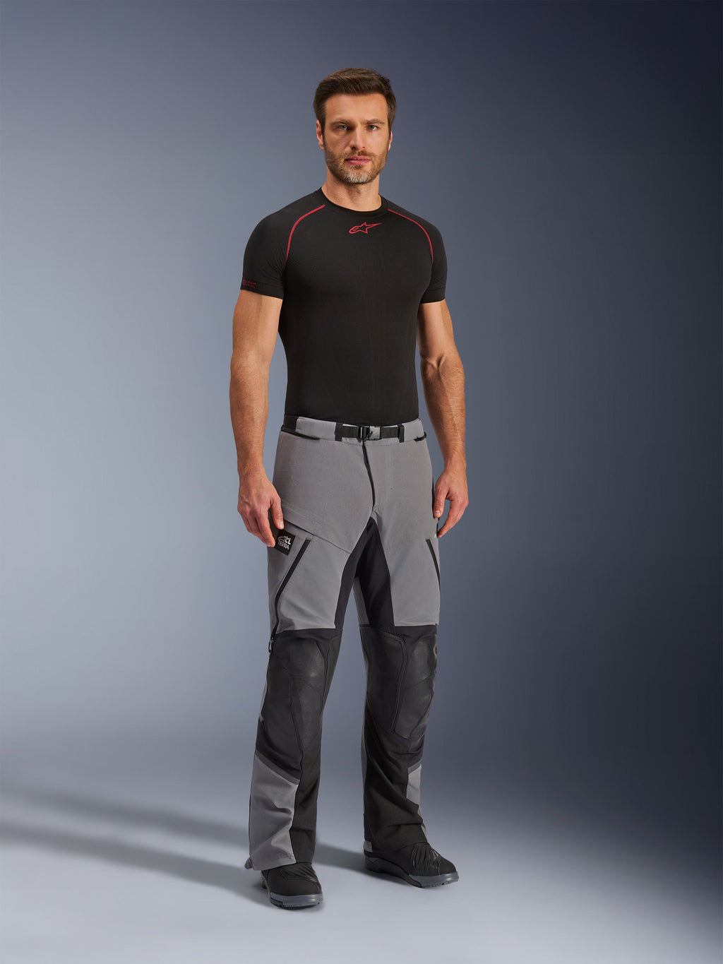 Alpinestars Andes Pro Drystar® XF bukser, motorcykel adventure-bukser, mørkegrå og sort, båret af en model med et sort teknisk basislag, multi-panel konstruktion med vandtætte lynlåse og forstærkede zoner til adventure-kørsel