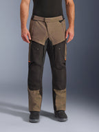 Alpinestars Cusco Drystar® bukser, adventure touring motorcykelbukser, valnød og sort med orange detaljer, set forfra på model, med teknisk tekstilkonstruktion, cargolommer og ventilationslynlåse, båret med sorte kørestøvler