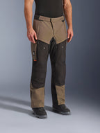 Alpinestars Cusco Drystar® bukser, adventure motorcykelbukser, Walnut Black, vist på en model med sorte støvler, med et brunt og sort multi-panel design med lynlåslommer og forstærkede knæ til touring