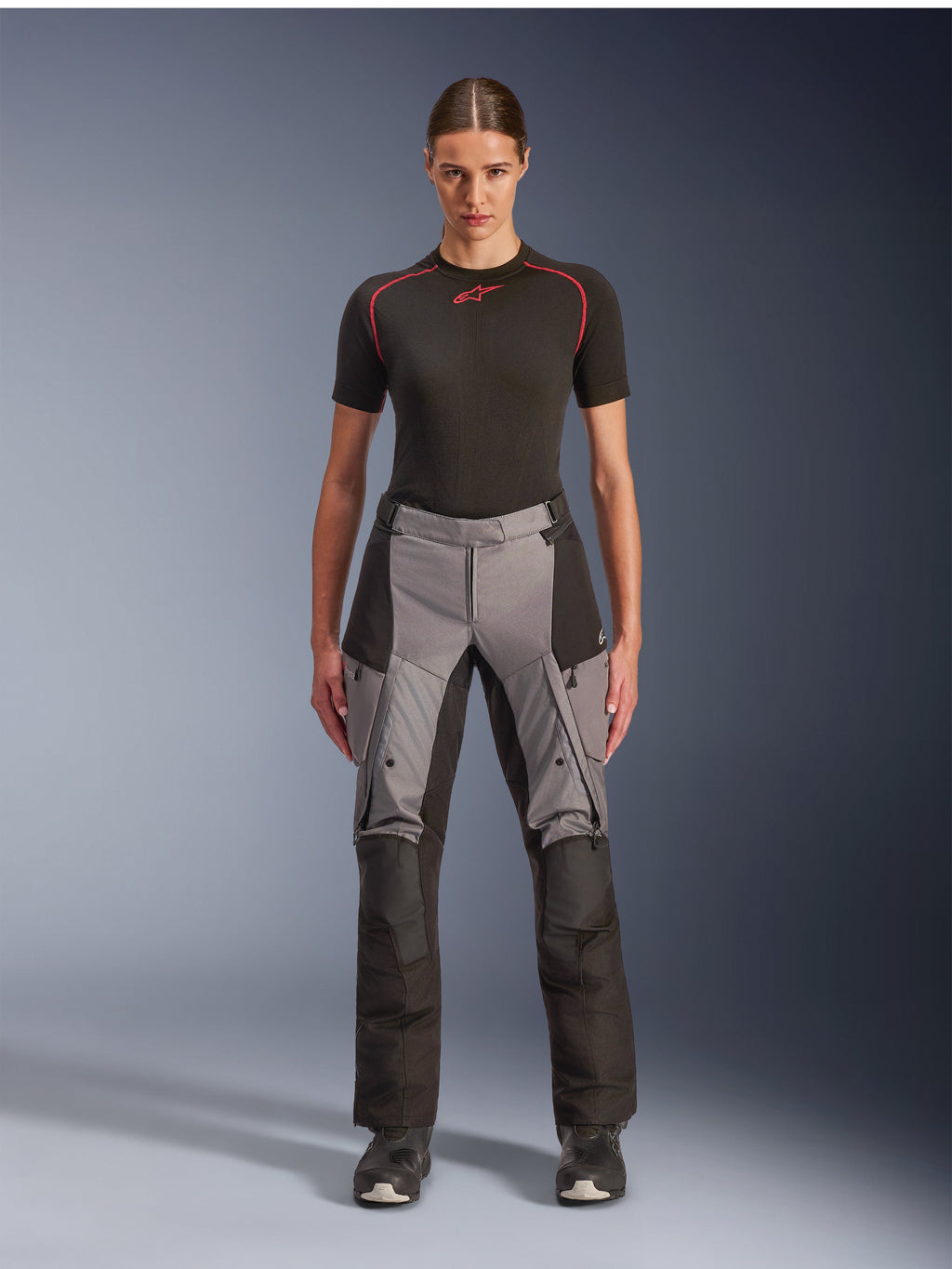 Alpinestars Stella Andes V4 Drystar bukser, eventyr-touring motorcykelbukser til kvinder, sort og mørkegrå, båret af en kvindelig model med et sort basislag og motorcykelstøvler, med forstærkede tekstilpaneler og cargolommer til eventyrkørsel