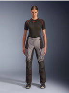 Alpinestars Stella Andes V4 Drystar bukser, eventyr-touring motorcykelbukser til kvinder, sort og mørkegrå, båret af en kvindelig model med et sort basislag og motorcykelstøvler, med forstærkede tekstilpaneler og cargolommer til eventyrkørsel