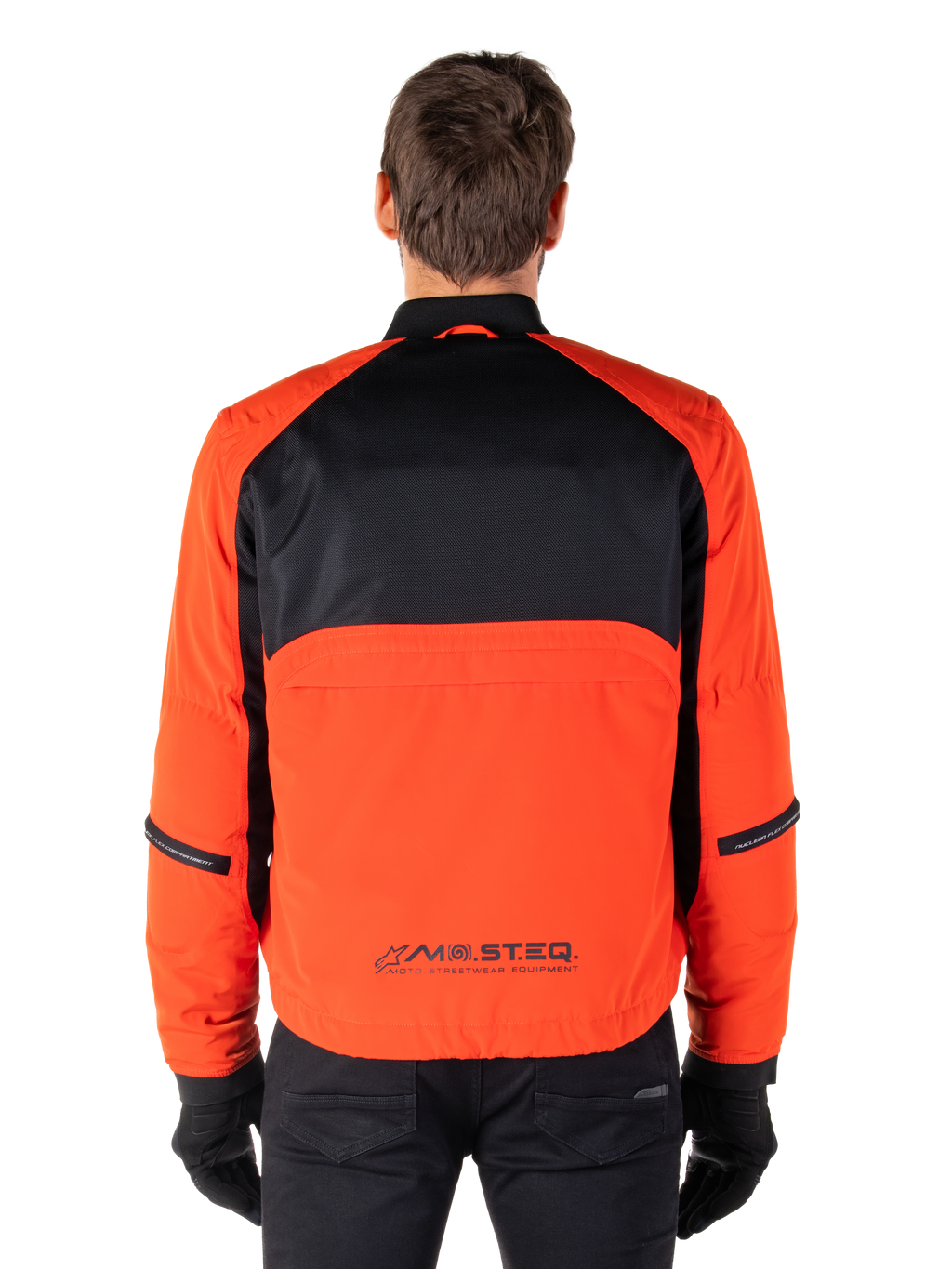Alpinestars Mootant vandtæt parka, motorcykeljakke, Spicy Orange og sort, set bagfra, med sort mesh på den øverste del af ryggen og orange panel forneden med MO.ST.EQ.-logo, båret med sorte bukser og handsker