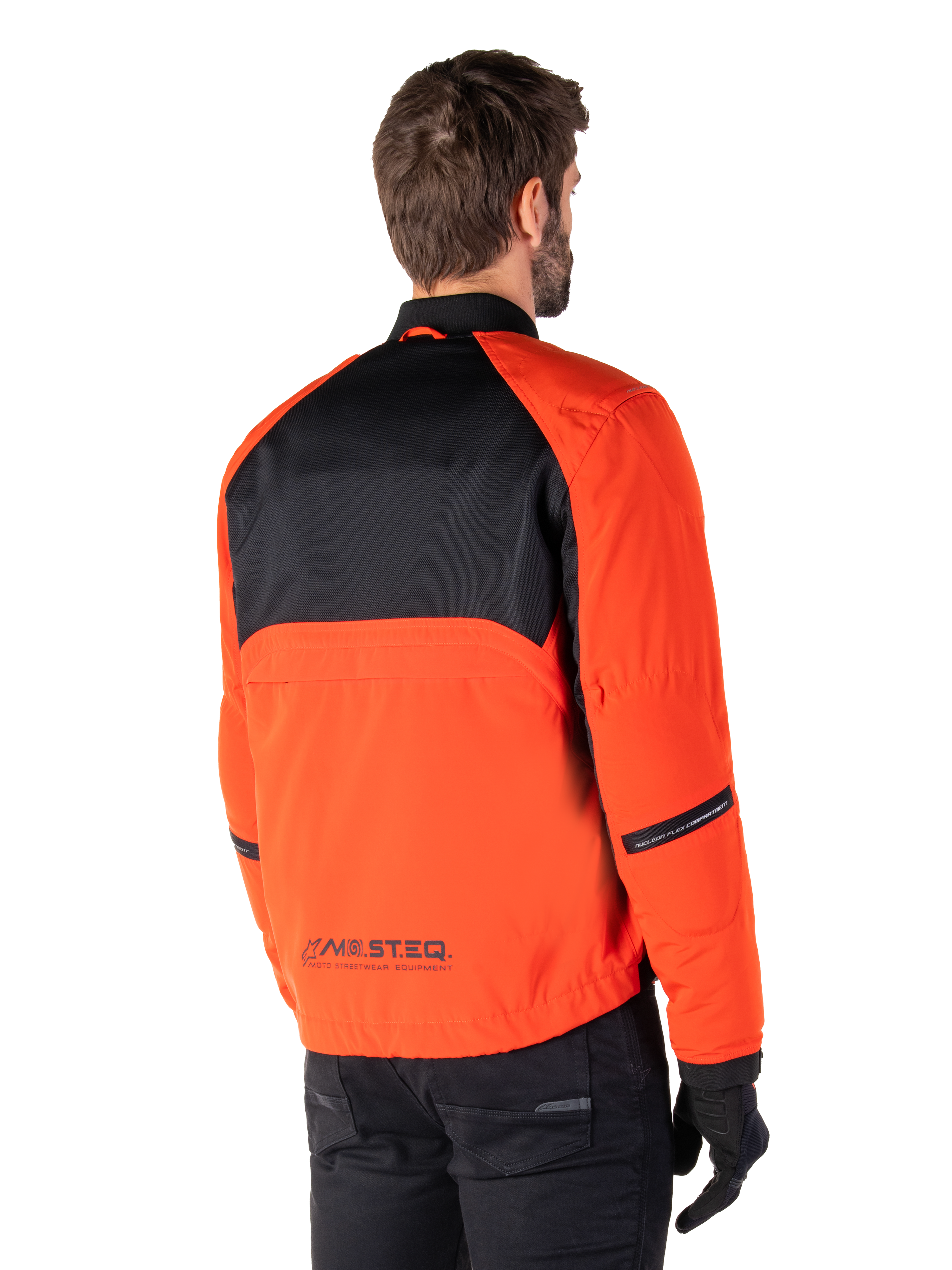 Set bagfra af en kører iført Alpinestars Mootant Waterproof Parka i Spicy Orange og sort, med et sort mesh-panel på den øverste del af ryggen og reflekterende MO.ST.EQ.-branding, moderne utilitaristisk motorcykeljakke