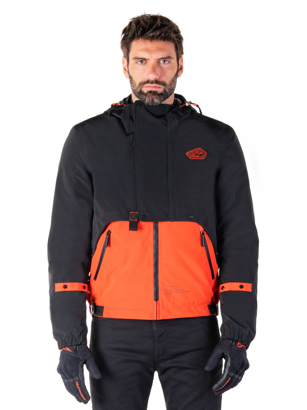 Alpinestars Mootant Waterproof Parka, modulær motorcykeljakke i Spicy Orange og sort, båret af en model med matchende handsker, design med hætte og tofarvede paneler, lynlås foran og justerbare manchetter, moderne urbant køreudstyr